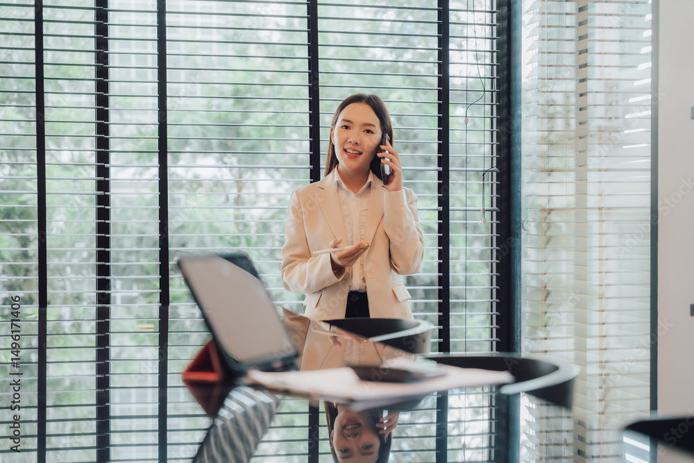 Fototapeta premium Confident Asian Businesswoman Talking on Phone in Office