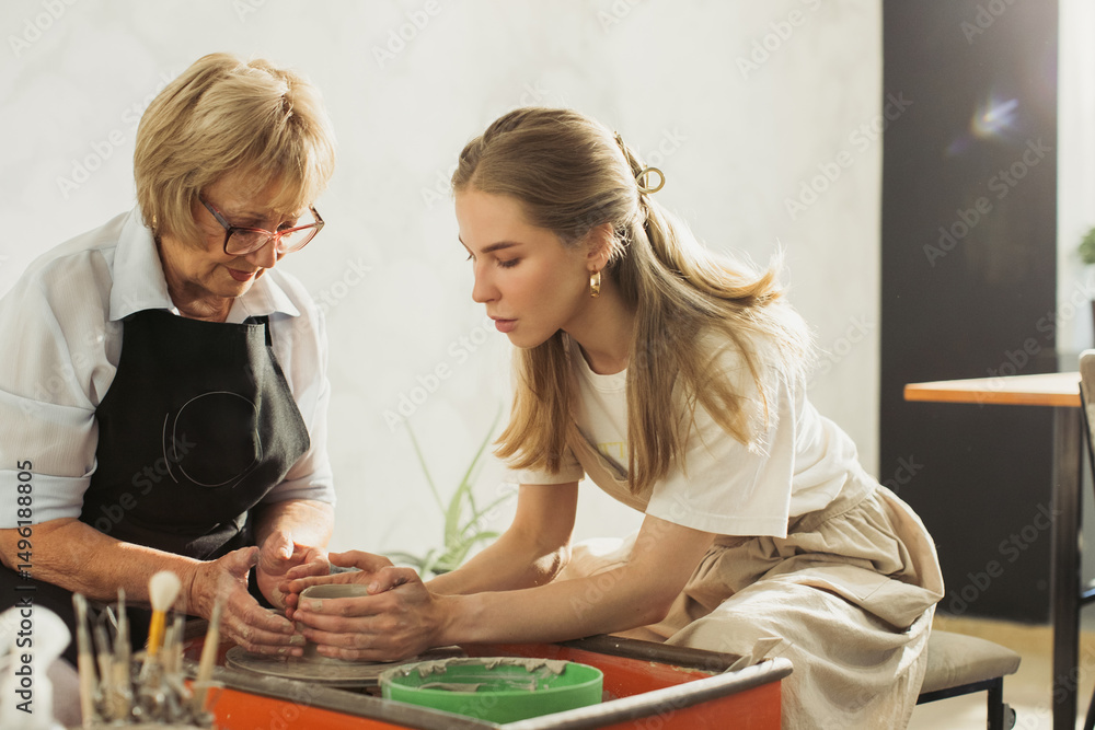 Fototapeta premium Senior woman learning pottery making with young instructor