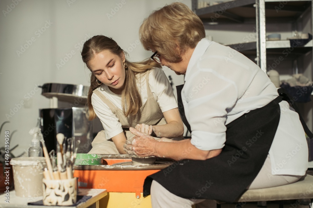 Obraz premium Senior potter teaching apprentice clay modeling on pottery wheel