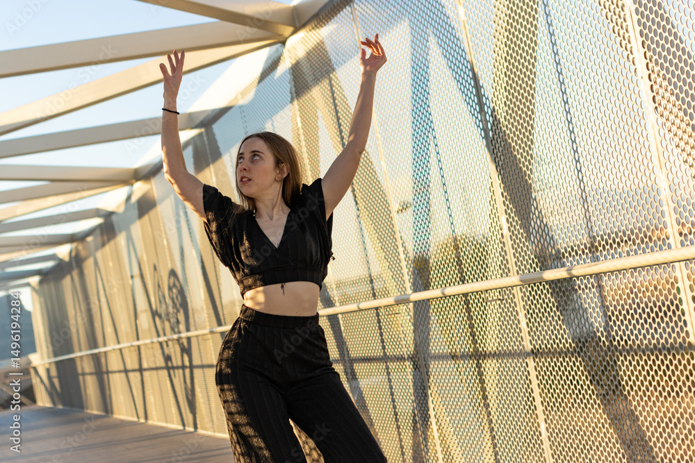 Young dancer performing modern dance on a bridge at sunset Young dancer performing modern dance on a bridge at sunset