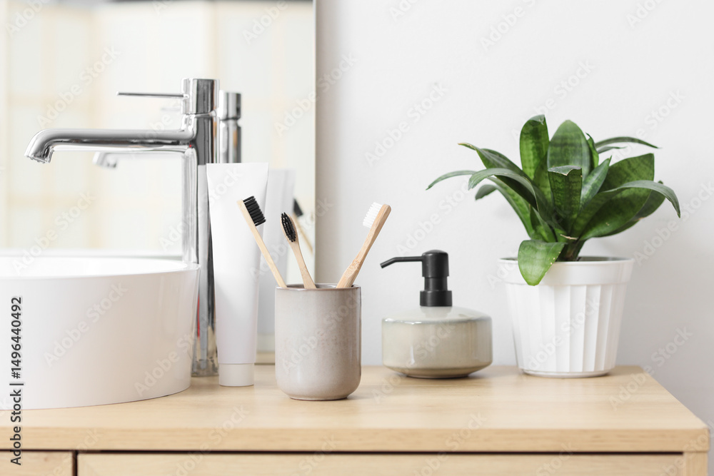Fototapeta premium Holder with bamboo tooth brushes and paste on stand near sink in bathroom