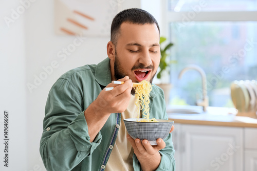 Young man eating tasty rame...