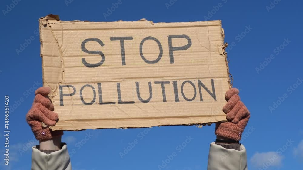 a sign that reads Stop pollution against the backdrop of the sky. The protester is raising awareness about the issue of environmental protection and the need to preserve land. a sign that reads Stop pollution against the backdrop of the sky. The protester is raising awareness about the issue of environmental protection and the need to preserve land.