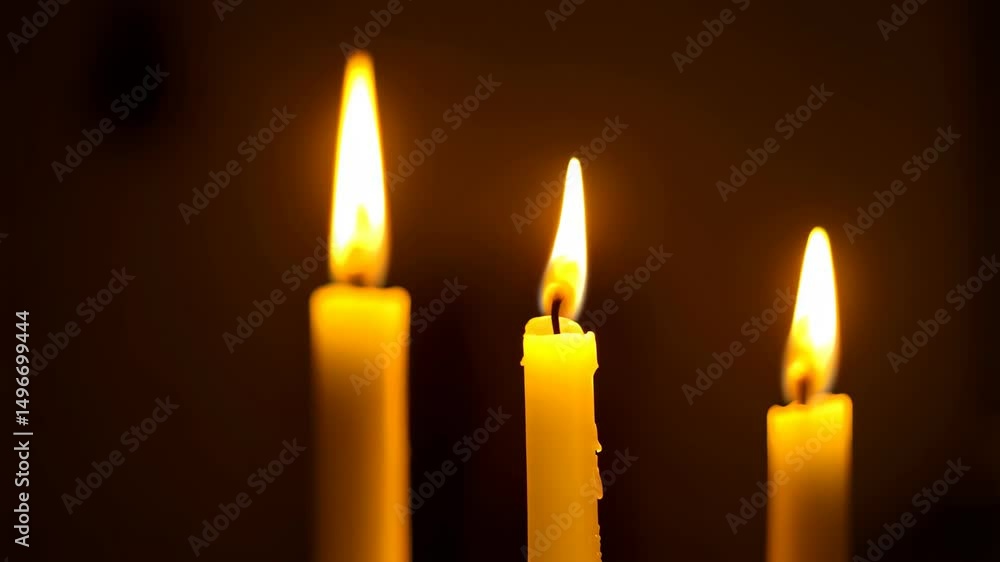 Three burning candles illuminating the darkness, their flames flickering with a warm, inviting glow in a close-up shot. Three burning candles illuminating the darkness, their flames flickering with a warm, inviting glow in a close-up shot.