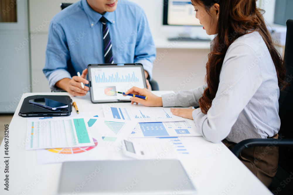 Obraz premium Two professionals reviewing business charts and data with tablet and documents. Ideal for financial planning, corporate teamwork, and modern office