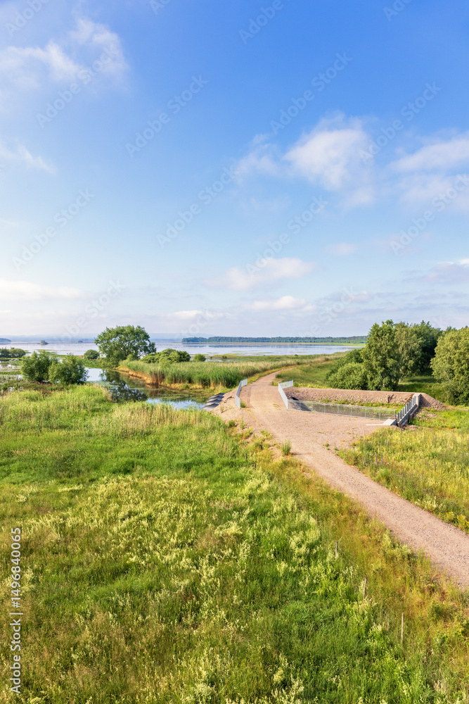 Dirt road over a dam by a lake in a beautiful summer landscape Dirt road over a dam by a lake in a beautiful summer landscape