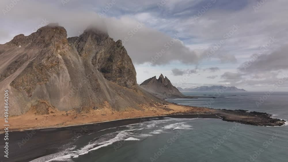 Vestrahorn, Eystrahorn and Brunnhorn peaks along Stokksnes coastline aerial view, stunning Icelandic landscape with black sands, ocean waves and skies. Vestrahorn, Eystrahorn and Brunnhorn peaks along Stokksnes coastline aerial view, stunning Icelandic landscape with black sands, ocean waves and skies.