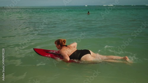 Old woman learns to surf. Senior female goes surfing with surfboard, beginner student. First lesson