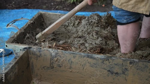 足で踏んで荒壁土を作る男性