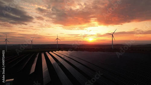 Drone view of windmill turbines generating green energy electric.	
Green energy reduce carbon emissions and makes earth cleaner and more ecological. Solar panels park and wind turbines at sunset.