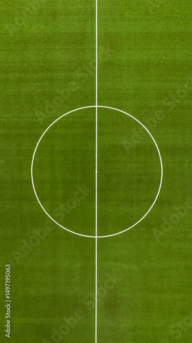 Aerial perpendicular closeup of the midfield circle in an empty synthetic grass football field. Here the kick off is taken in a game of soccer.