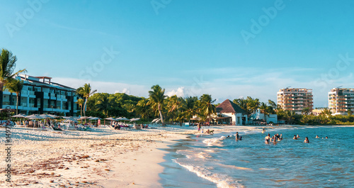 Tropical Caribbean beach people parasols fun Playa del Carmen Mexico.