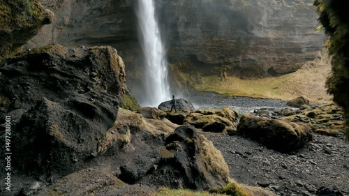 Iceland, Kvernufoss Waterfall near Skogafoss [4K] - A hiker walks face to face with the waterfall, plunging for 30 meters into a moss-covered scenic gorge in south Iceland