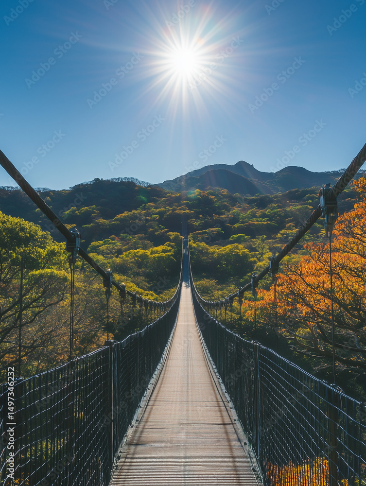 Obraz premium Suspension bridge leading to the sunny mountain in autumn