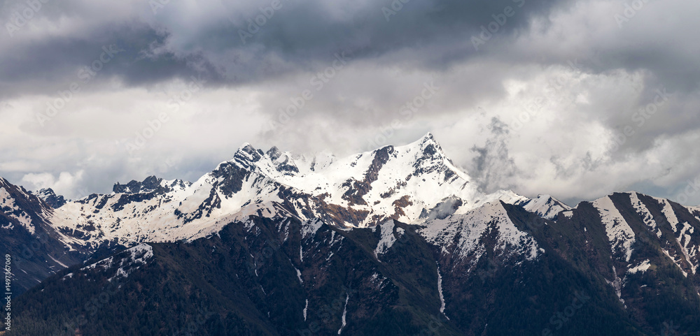 Obraz premium Sweeping panorama of the snow-dusted Pizzo dei Tre Signori mountain range under a vast, cloud-streaked sky, showcasing its jagged peaks and wild alpine beauty. Orobie Alps, Lombardy
