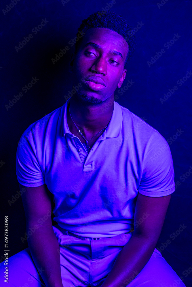 Young man posing under blue light in studio setting Young man posing under blue light in studio setting
