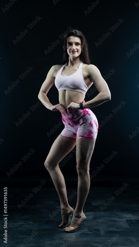 Obraz premium Confident fitness model posing on black background showing muscles 