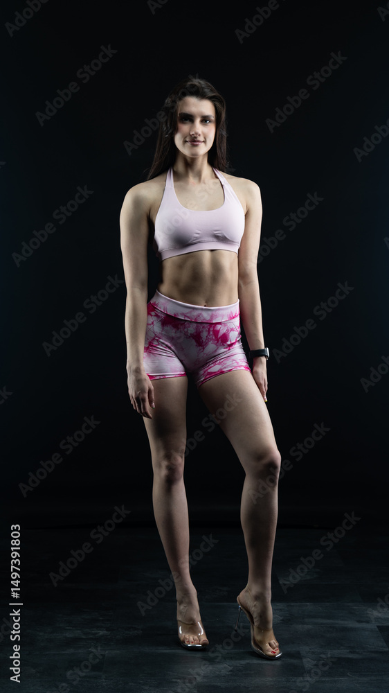 Obraz premium Confident fitness model posing on black background showing muscles 