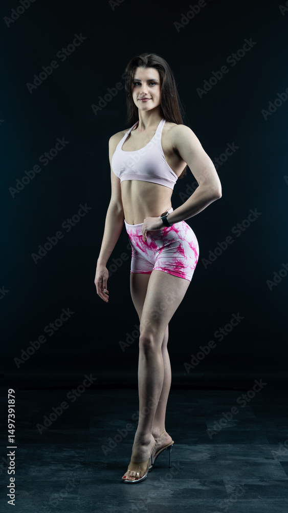 Obraz premium Confident fitness model posing on black background showing muscles 