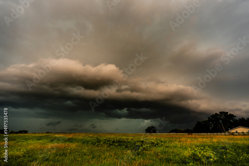 A shelf cloud creeps over hills under an ominous, dramatic sky, filled with shadow, texture, and moving clouds, signaling danger, stormy weather, and the raw power of nature outdoors.