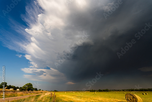 Bright sunshine fades to dark as storm clouds move over fields, creating a dramatic sky filled with texture, shadow, and moody atmosphere, capturing the shifting beauty and power of weather.