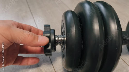 Slow-motion video of assembling a dumbbell focusing on the detailed process of screwing a metal nut onto a bar. The close-up view highlights the precision, texture, and mechanical movement, creating a