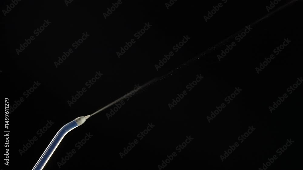 Portable oral irrigator on black background, close up. Dental teeth whitening, flosser bucal tooth cleaner, waterpulse, water thread for teeth. Stream of water from an irrigator nozzle Portable oral irrigator on black background, close up. Dental teeth whitening, flosser bucal tooth cleaner, waterpulse, water thread for teeth. Stream of water from an irrigator nozzle