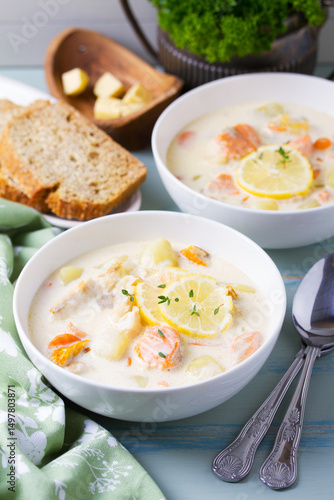 Fish and shrimp cream soup in white bowls on blue table