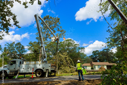Photography Workers operate bucket truck to repairs power lines in suburban neighborhood after storm