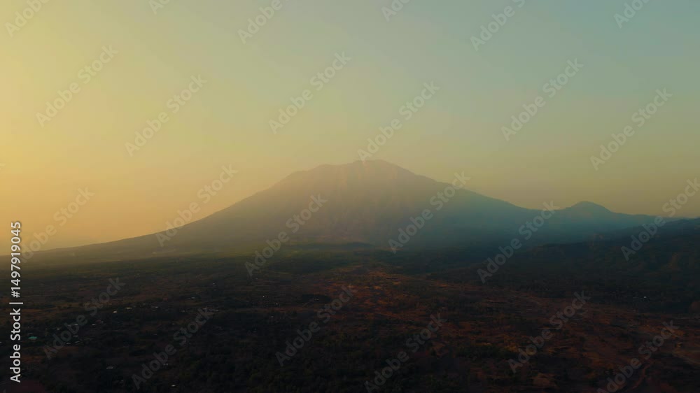 A stunning sunrise over Mount Batur and Mount Agung in Bali reveals mist-covered settlements and lush green plantations. The early light casts a serene glow over the breathtaking landscape. A stunning sunrise over Mount Batur and Mount Agung in Bali reveals mist-covered settlements and lush green plantations. The early light casts a serene glow over the breathtaking landscape.