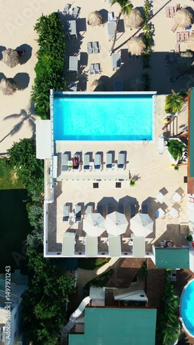 Top-down view of a tourist hotel with a rooftop pool located on a tropical beach