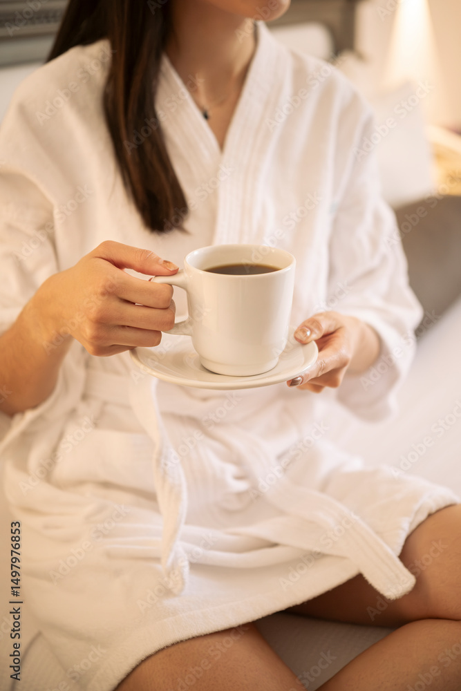 Mujer en bata de hotel tomando una taza de café Mujer en bata de hotel tomando una taza de café