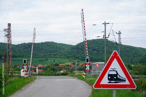 An open level crossing with barriers that allow the railroad tracks to be crossed. In a rural landscape near Alfeld, Lower Saxony, Germany.