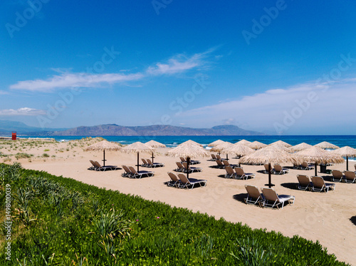 Beautiful Episkopi beach, Rethymnon, Crete, Greece. Sun loungers in rows on the gently shelving sands. Typical Greek summer scene.