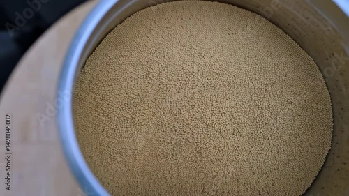 Thousands of tiny, pale yellow amaranth seeds creating a dense abstract background texture, food ingredient with potential health benefits.