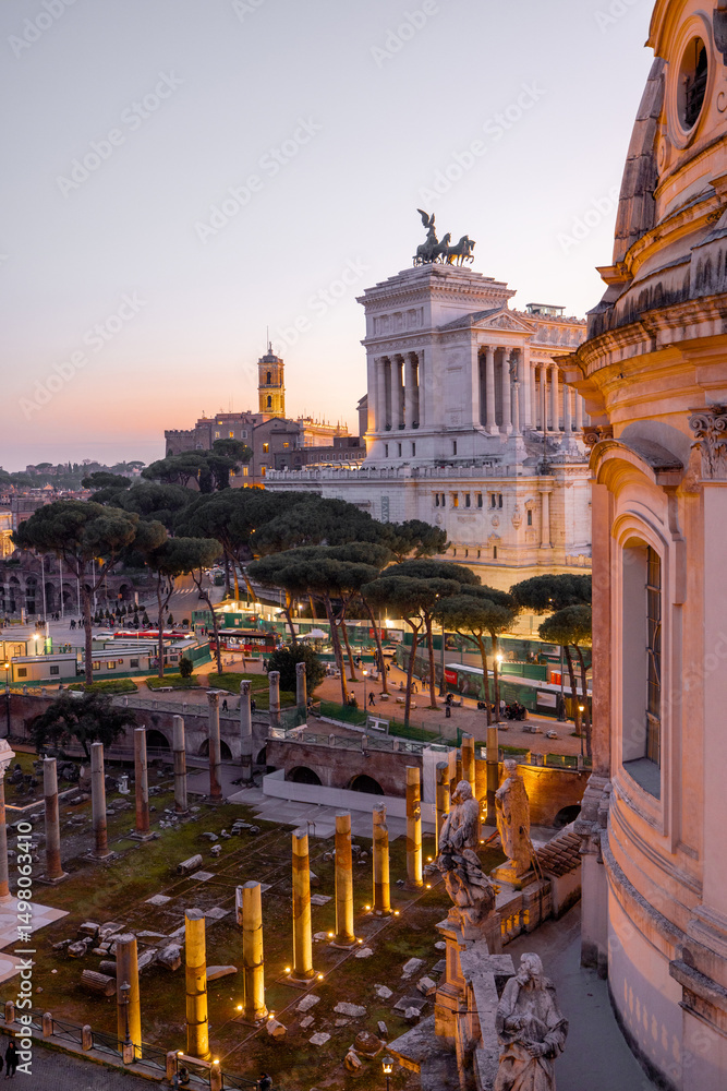 Obraz premium Scenic view of a historic dome and ancient Roman ruins glowing in the sunset light. The iconic Altare della Patria rises in the background above Romes evening skyline