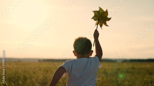 Fotografija Happy child playing with toy pinwheel outdoors in summer in park against blue sky