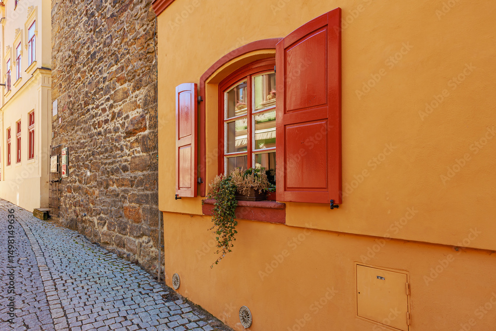 Fototapeta premium Charming european street with colorful building facade and red shuttered window