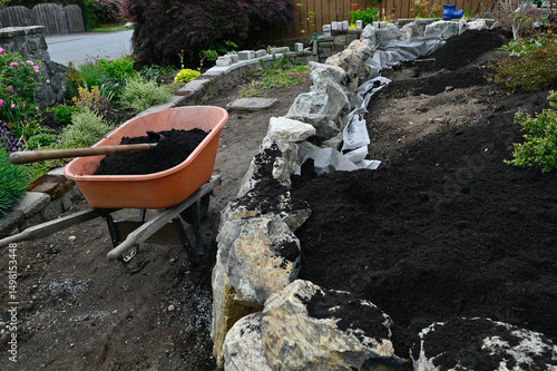 Landscape design project of stacked stone wall in progress in yard and garden