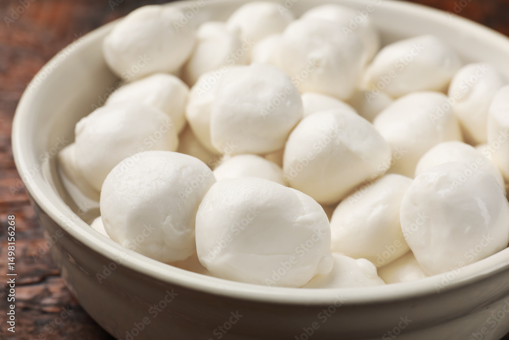 Tasty mozzarella cheese balls in bowl on wooden table, closeup Tasty mozzarella cheese balls in bowl on wooden table, closeup