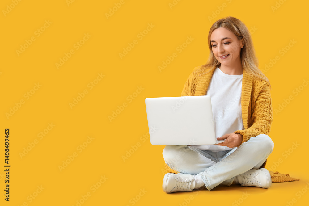 Naklejka premium Mature woman using laptop on yellow background