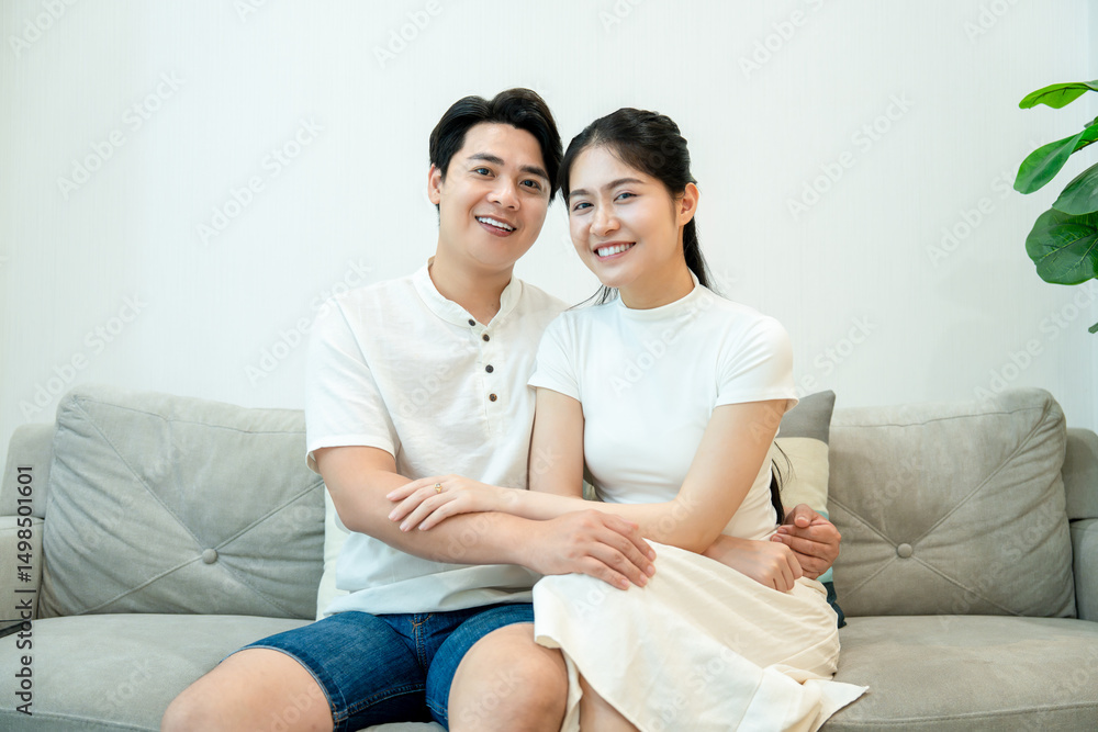 young asian couple sitting on sofa talking happily young asian couple sitting on sofa talking happily