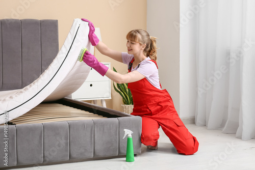 Female janitor cleaning mat...