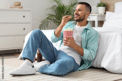 Young man with popcorn watc...