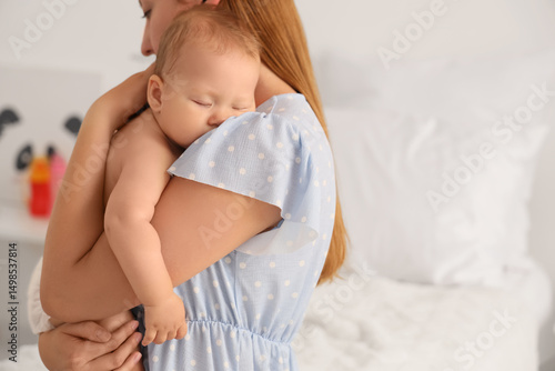 Young mother with her sleeping newborn baby in maternity hospital, closeup