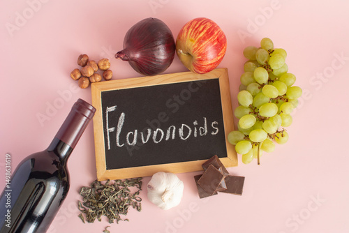 Products containing flavonoids in their composition. Grapes, onions, garlic, chocolate, tea, close-up on a light background and the inscription flavonoids on a dark board