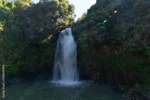 waterfall cascading down lush green cliff into a pool below