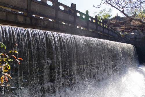 Canvas Print waterfall flowing beneath ancient stone bridge in scenic garden