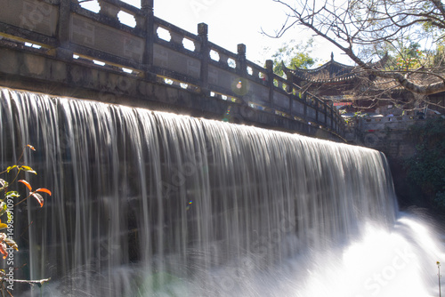 Photography waterfall flowing beneath ancient stone bridge in scenic garden