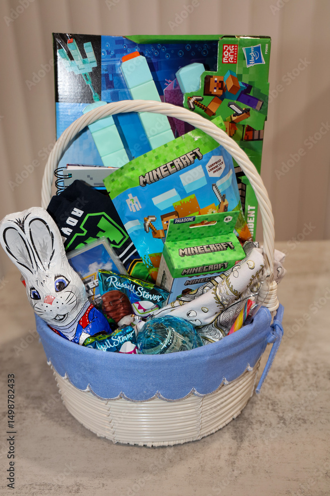 Naklejka premium San Diego, CA USA on April 18, 2025. Homemade Easter basket idea for boys. Easter basket filled with toys, candy, money and t-shirt.